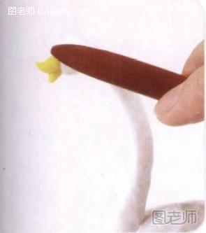步骤5:将黄色软陶揉成圆锥体，剪开粘在头部做嘴，并调整嘴形