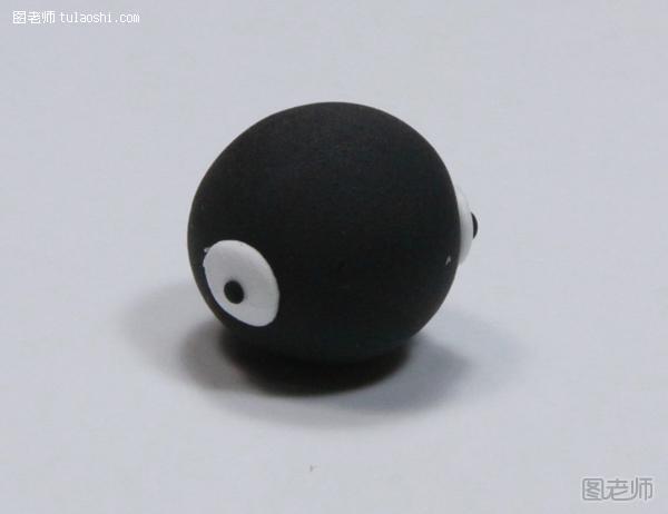 步骤7:揉一个黑色圆球，两边贴白色小圆片，上粘黑点，做鸡头