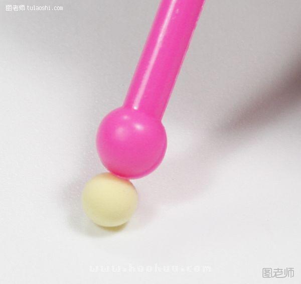 步骤3:做耳朵：用圆头棒按压黄色小球，然后同样按压粉红小球