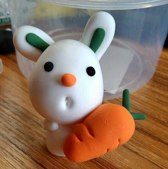 步骤9:把胡萝卜粘到小白兔身上，再搓一根白色小粗条，作小白兔的小手，如图位置粘上去