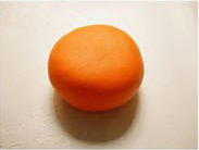 1.双手揉一个橘黄色圆球，将圆球压扁一点。