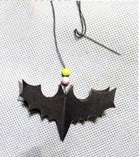 10.用针线把做好的蝙蝠组合串起来，增加几个装饰珠子、一个小铃铛。