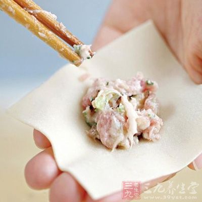取一张馄饨皮平放于掌心，用筷子夹取适量的肉馅放在馄饨皮的中央